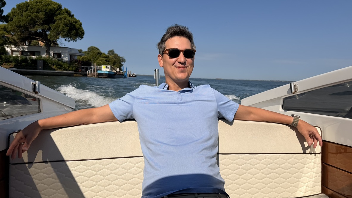 Sal smiling on a private water taxi in Venice, with the boat, woodwork, wake, and lagoon visible